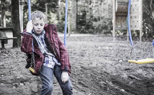 Sad boy sitting on a swing.