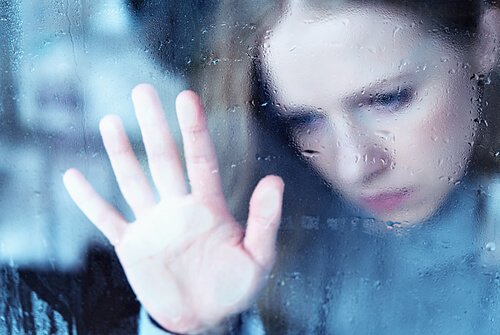 Sad woman looking out the window, confronting pain.