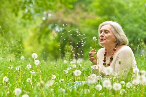 Elderly woman blowing a dandelion.