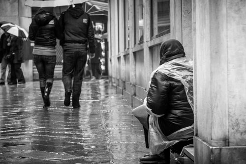 person der sidder på gaden i regnvejr