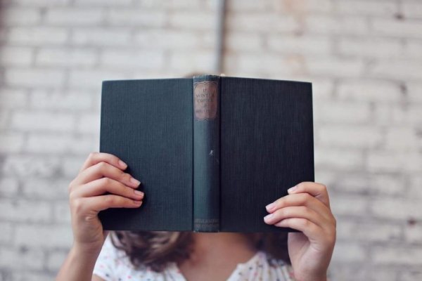 Woman covering her face with a book.