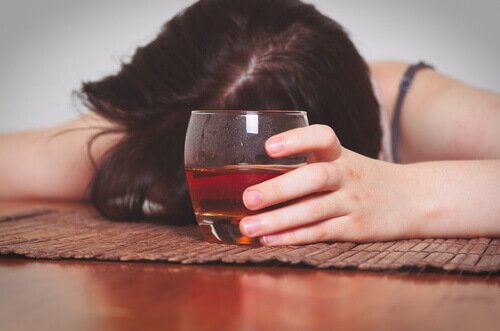 kvinde, der ligger henover bord med drink i hånden