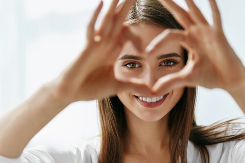 A woman making a heart with her fingers.
