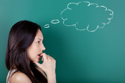 Woman thinking in front of a chalkboard.