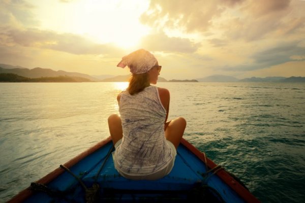 Woman who knows that traveling improves your brain health in a boat.