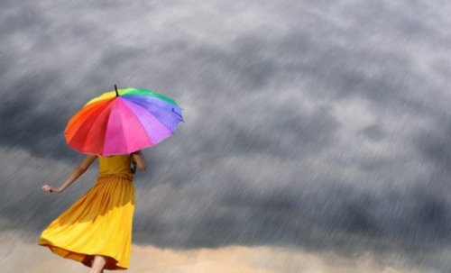 A woman with a colorful umbrella under a storm.
