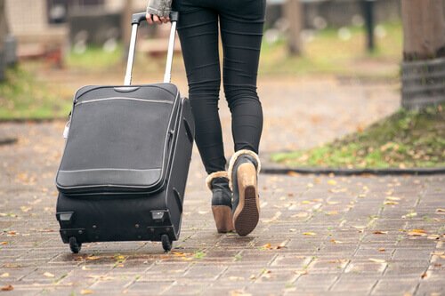 Woman in boomerang generation walking with suitcase.