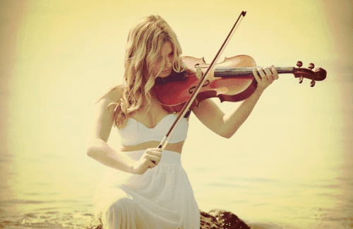 kvinde, der spiller på violin ved vandet