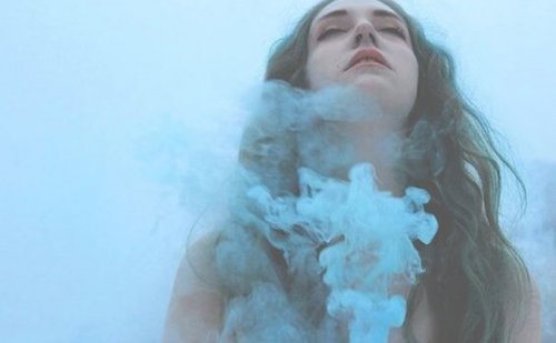 Brunette girl surrounded by blue smoke.