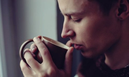 Man smelling a cup of coffee.