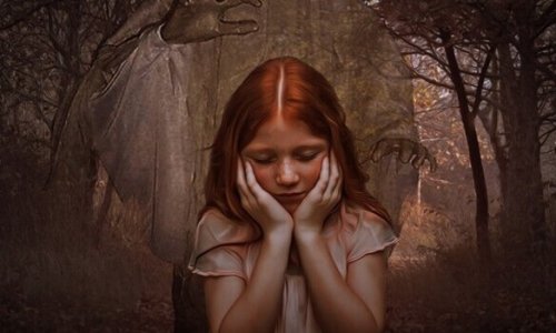 A redheaded girl in front of a forest.