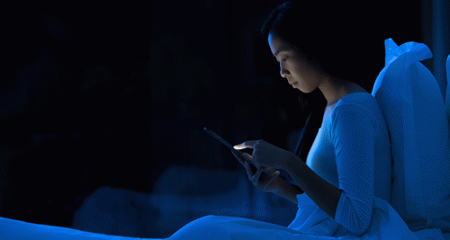 A woman in bed with her cell phone.