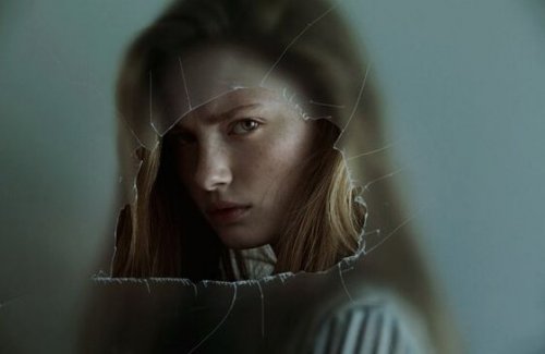 An angry girl looking through a glass.