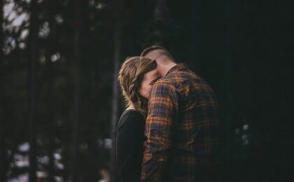 A couple hugging in the woods.