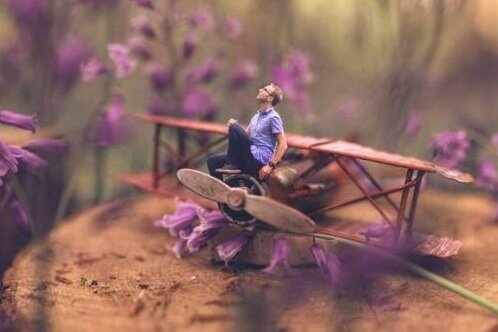 A guy sitting on a toy plane.