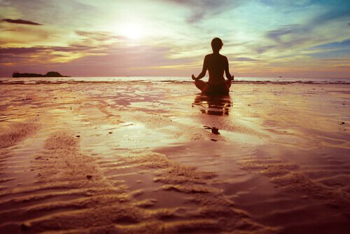 A person meditating on the beach.
