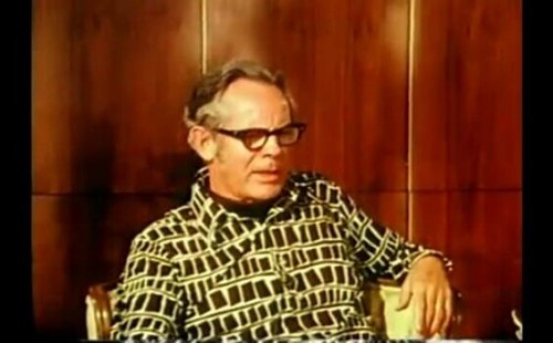 Rollo May sitting on a chair.
