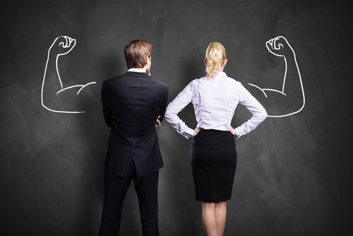 A couple in front of a chalkboard with strong arms drawn there.