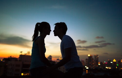 A couple looking at each other in front of the sunset.