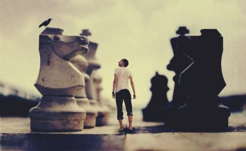 A man surrounded by giant chess pieces.