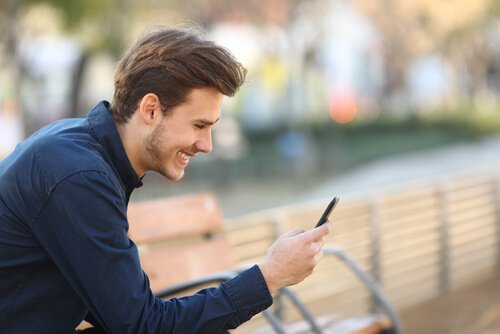 Man smiling and using phone.