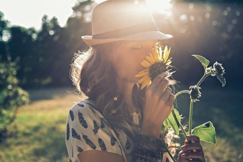 Woman smelling sunflower and reflecting on the importance of disconnecting yourself.