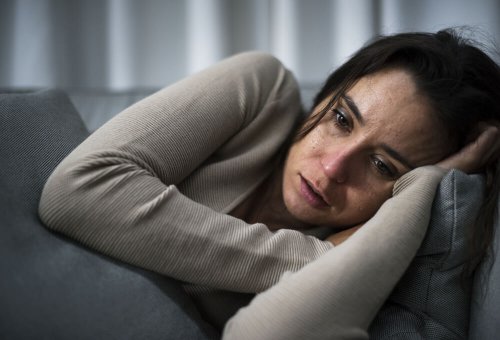 Woman with cognitive attentional syndrome crying on her couch.