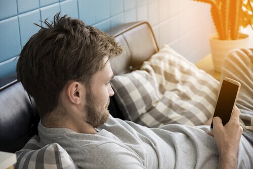 A guy looking at his phone, a habit that ruins sleep.