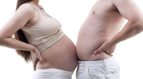 Man and pregnant woman bumping their bellies.