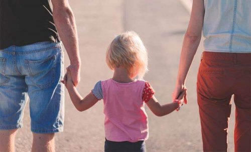 Child holding her parents' hands.