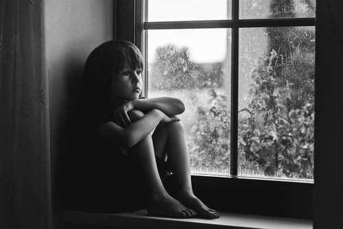 Sad kid looking through the window.