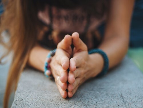 A woman bowing with her hands together, contemplating forgiveness.