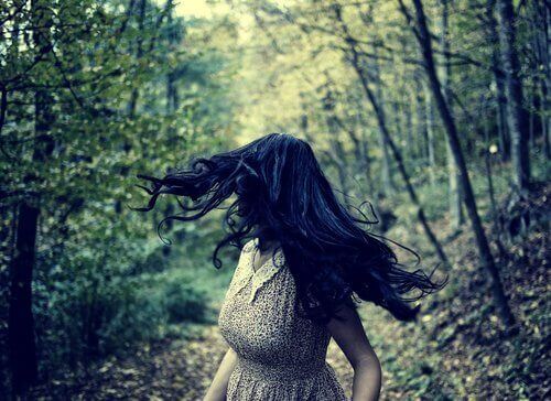 A woman running away in a forest.