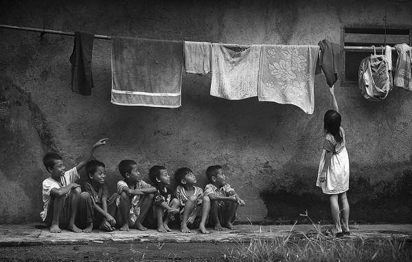 Boys looking at girl collecting clean clothes.