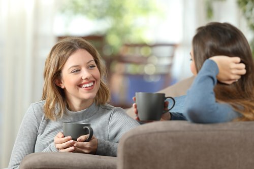 Two girlfriends laughing and drinking coffee.