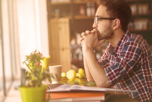 A man sitting in front of his computer and thinking about what it means to have attitude.