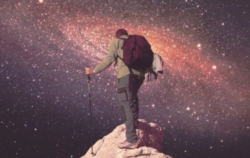 A man climbing to the top of a mountain under the starry sky.