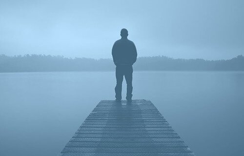 A man on a dock in the mist.
