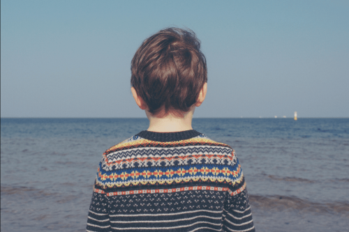 A grieving child looking out at the ocean.