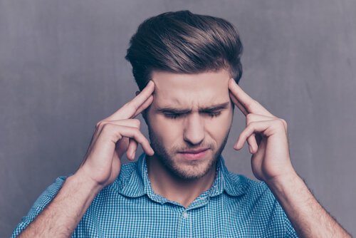 A guy with his eyes closed and his fingers on his temples.