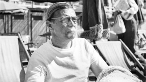 Jean-Paul Sartre sitting in a beach chair.