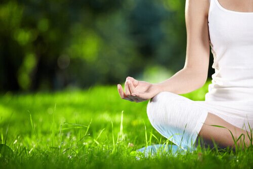 A woman meditating in the grass.
