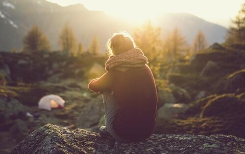 A woman on a mountain feeling emotional distance.