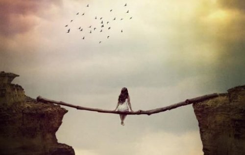 A woman sitting on log over a chasm.