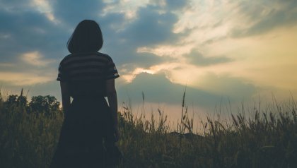 A woman standing in a field at dusk.