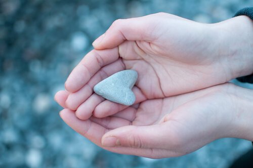 Hands holding a heart-shaped rock.
