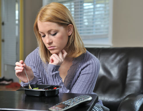 Woman looking sad, eating alone.