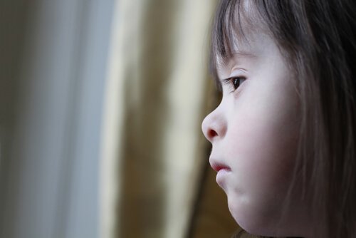 A girl with Down syndrome looking out the window.