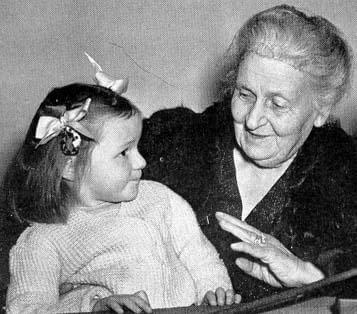 Maria Montessori talking to a little girl.