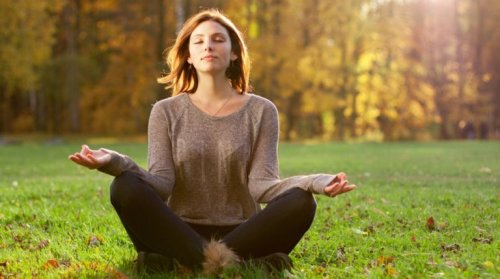 A woman meditating in the woods.